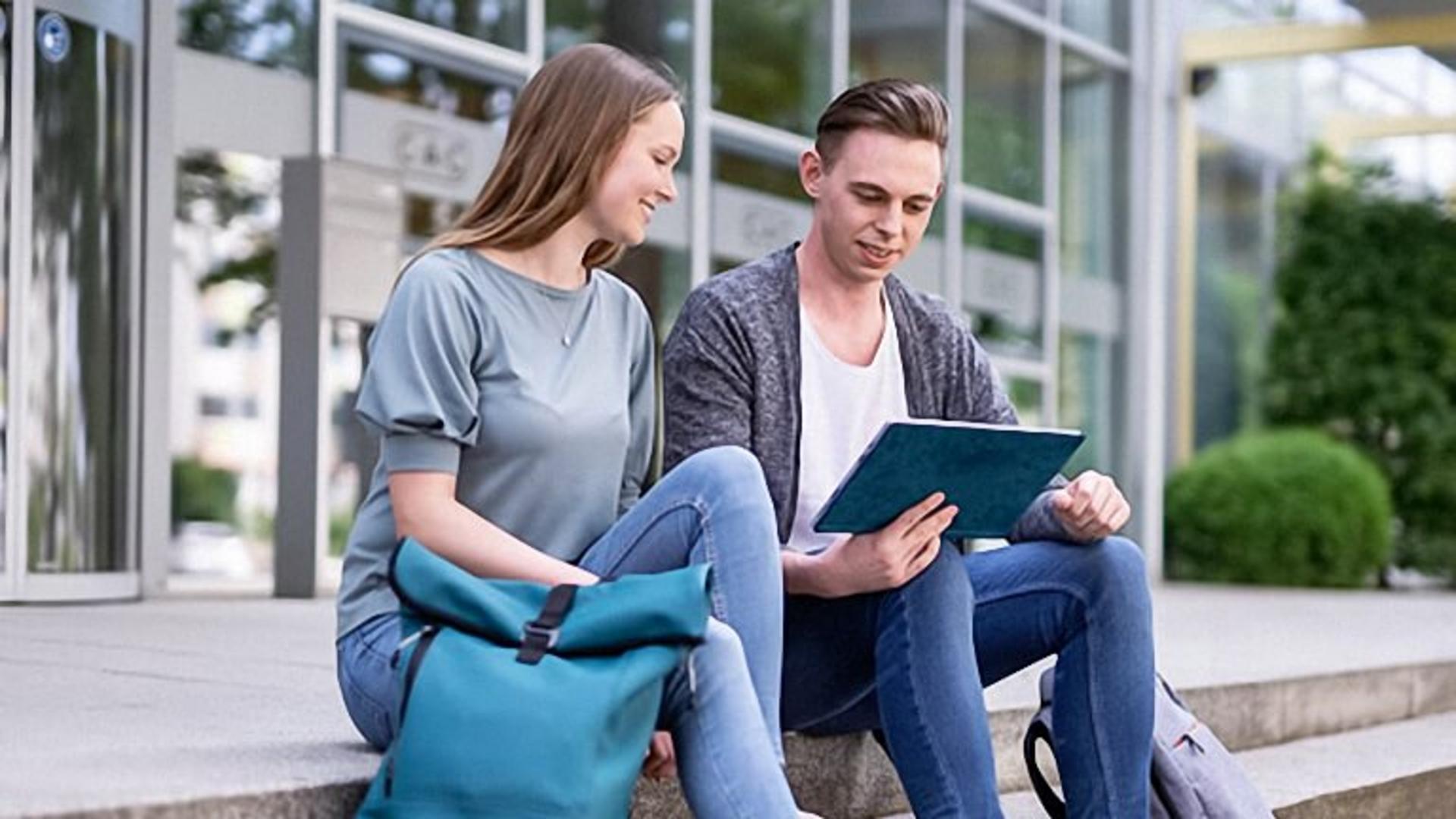 Studenten im Gespräch. Blick aufs Tablet.